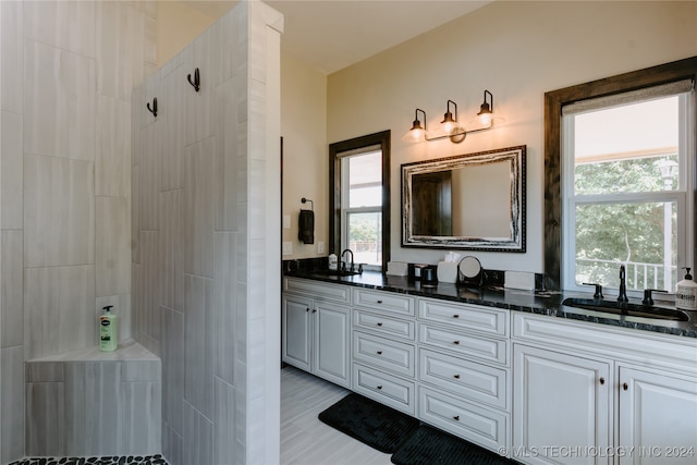 bathroom with a tile shower and vanity