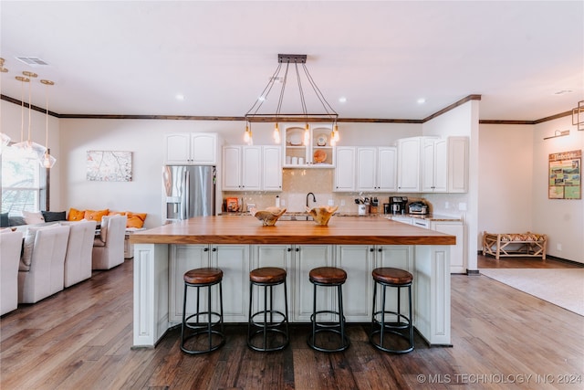 kitchen featuring white cabinets, stainless steel refrigerator with ice dispenser, hardwood / wood-style flooring, and decorative light fixtures