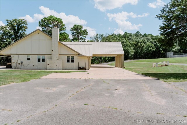 4100 N 430th Rd, Locust Grove, OK 74352 - view of side of property with an attached carport, a chimney, a lawn, driveway, and board and batten siding
