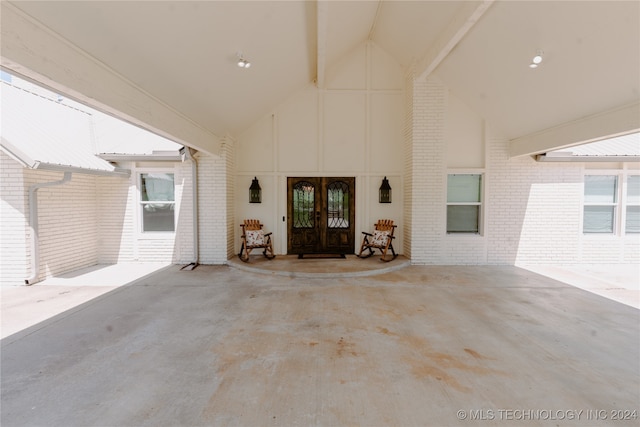 unfurnished living room with brick wall, beamed ceiling, and high vaulted ceiling