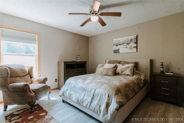 bedroom with ceiling fan, a textured ceiling, and light hardwood / wood-style flooring