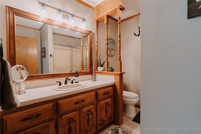 bathroom featuring walk in shower, ornamental molding, vanity, and toilet