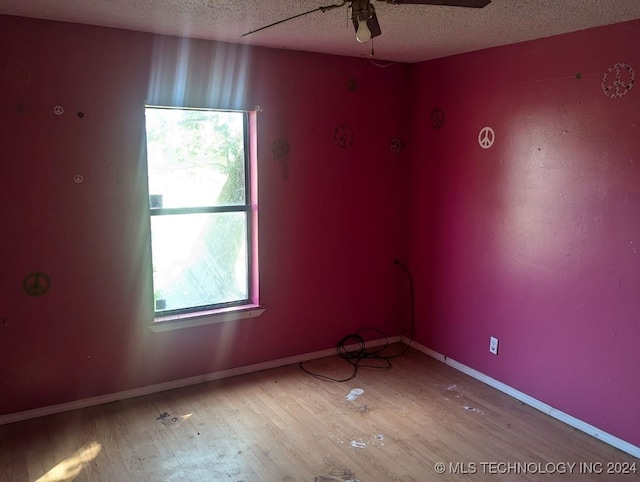 spare room with a wealth of natural light, ceiling fan, and wood-type flooring