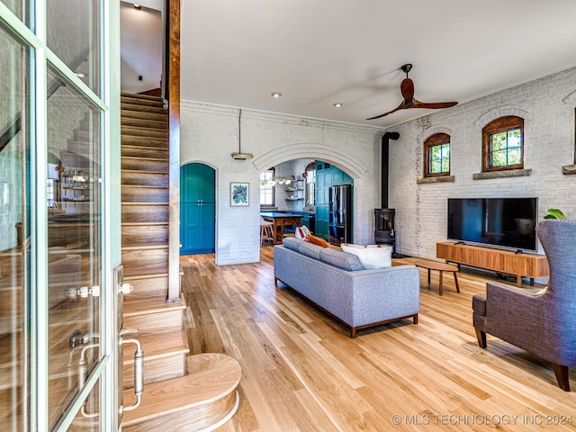 living room featuring ceiling fan, a wood stove, and hardwood / wood-style floors