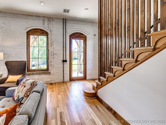entrance foyer with plenty of natural light, wood finished floors, brick wall, and stairway