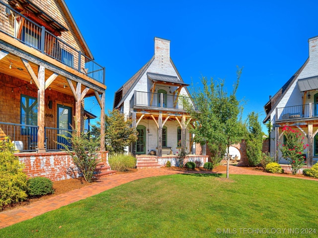 rear view of house with a lawn, a balcony, and a porch