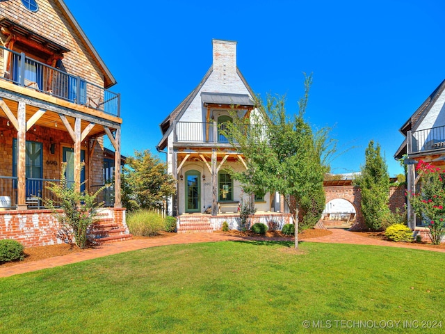 view of front of house featuring a front lawn and a balcony