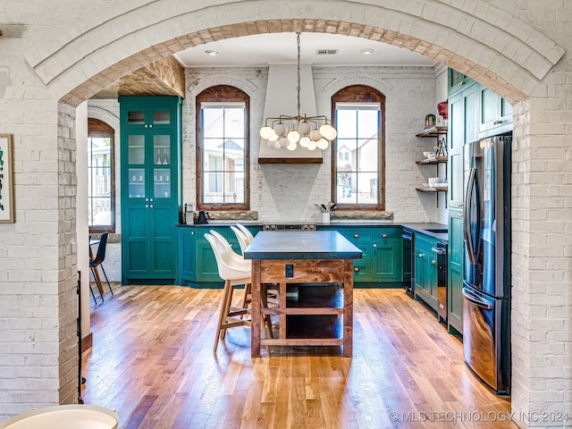 kitchen with light hardwood / wood-style flooring, stainless steel refrigerator, decorative light fixtures, and a chandelier