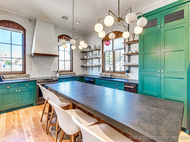 kitchen featuring custom range hood, a breakfast bar, sink, a notable chandelier, and stainless steel range with electric cooktop