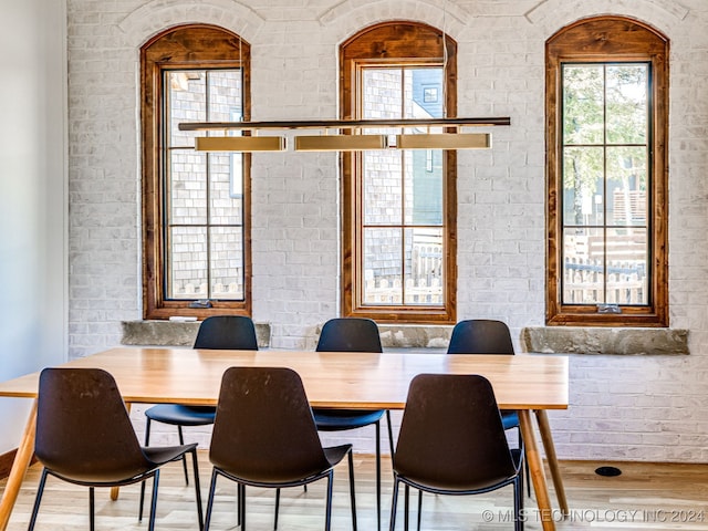 dining space featuring hardwood / wood-style floors and brick wall