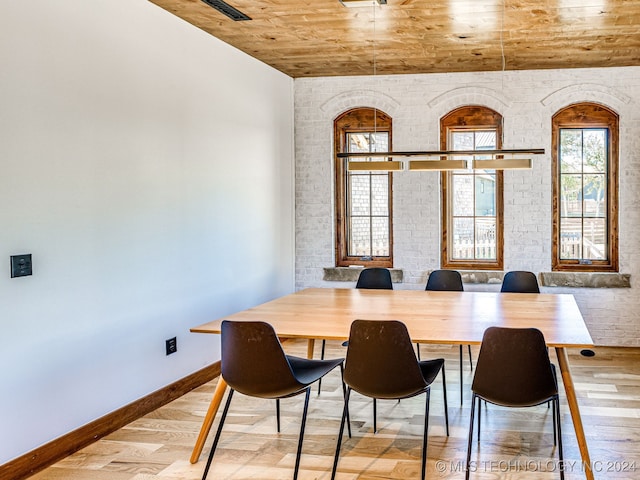 dining area with brick wall, light hardwood / wood-style flooring, and wooden ceiling