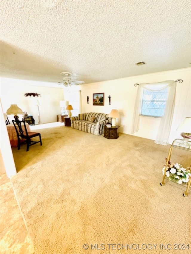 living area featuring a textured ceiling, carpet, and ceiling fan