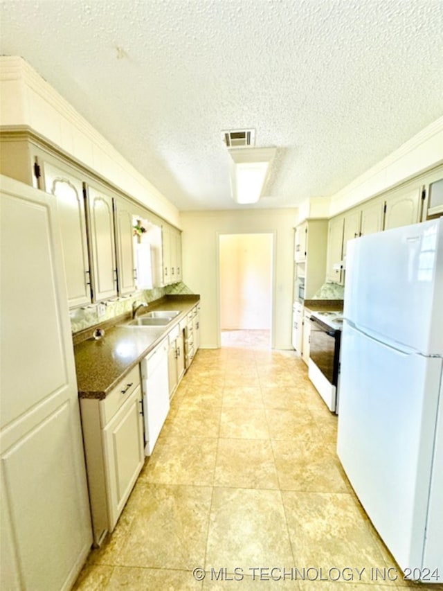 kitchen with sink, white appliances, light tile patterned floors, and a textured ceiling