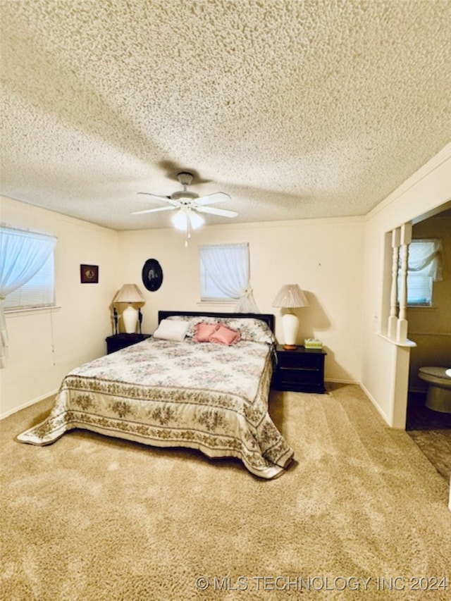 bedroom with ceiling fan, light colored carpet, and a textured ceiling