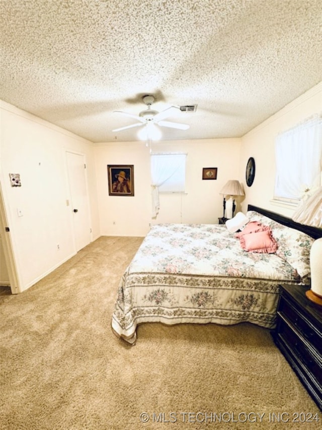 bedroom featuring ceiling fan, carpet floors, and a textured ceiling