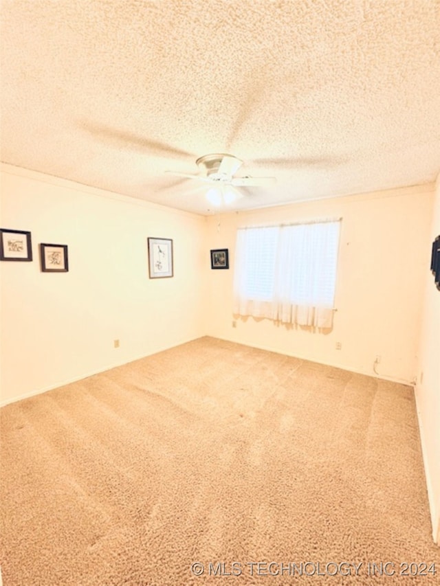 carpeted spare room featuring ceiling fan and a textured ceiling