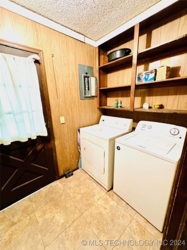 washroom with electric panel, washer and clothes dryer, a textured ceiling, and wood walls