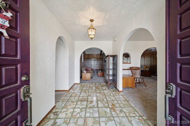 carpeted foyer entrance with a textured ceiling