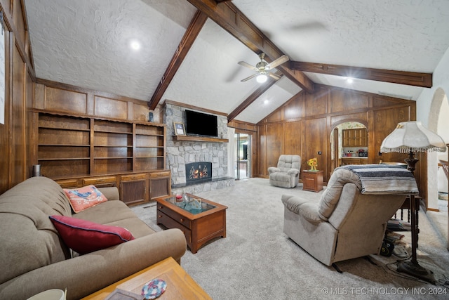 carpeted living room featuring a textured ceiling, a fireplace, wood walls, and ceiling fan