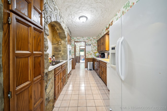 kitchen with a textured ceiling, white appliances, and light tile patterned floors