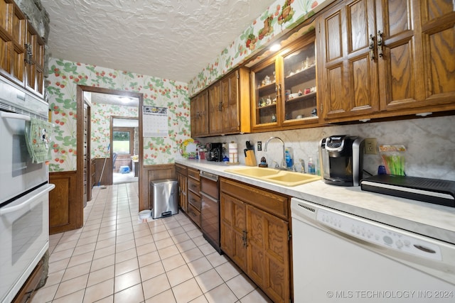 kitchen featuring white appliances, a textured ceiling, light tile patterned flooring, and sink