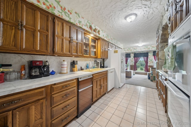 kitchen featuring light tile patterned floors, a textured ceiling, sink, and white appliances