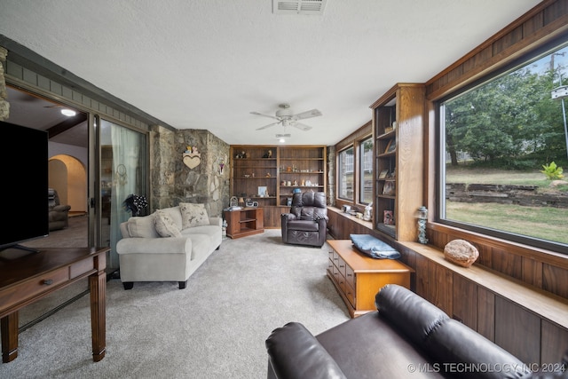 living room with ceiling fan, light colored carpet, a textured ceiling, and a healthy amount of sunlight