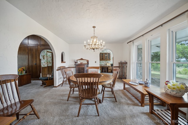 carpeted dining space featuring a textured ceiling and a chandelier