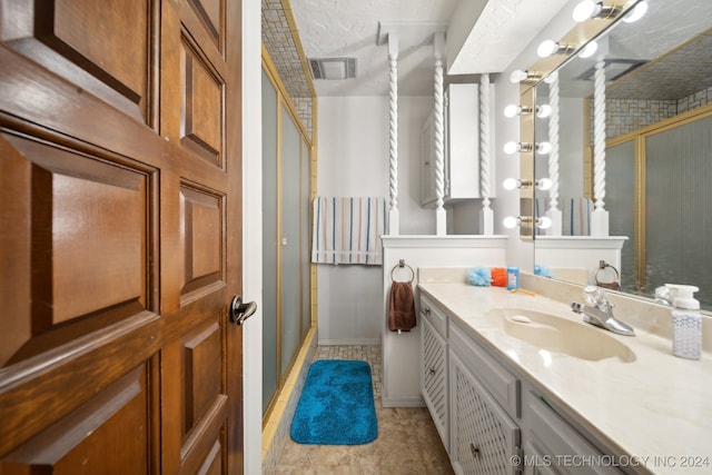 bathroom with walk in shower, vanity, a textured ceiling, and tile patterned floors