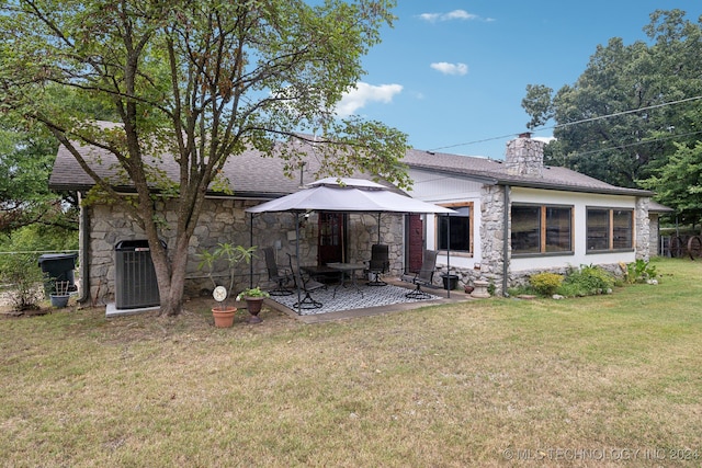 rear view of property with central AC unit and a lawn