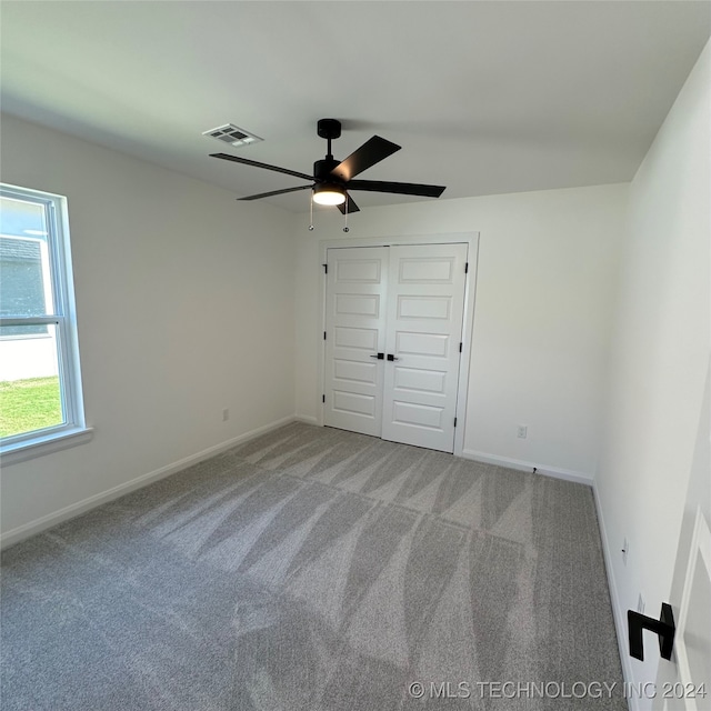 unfurnished bedroom featuring light carpet, a closet, and ceiling fan