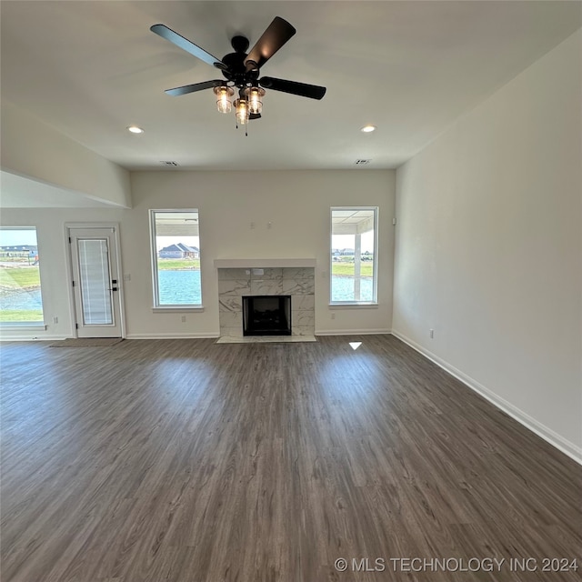 unfurnished living room featuring dark hardwood / wood-style floors, a tile fireplace, plenty of natural light, and ceiling fan