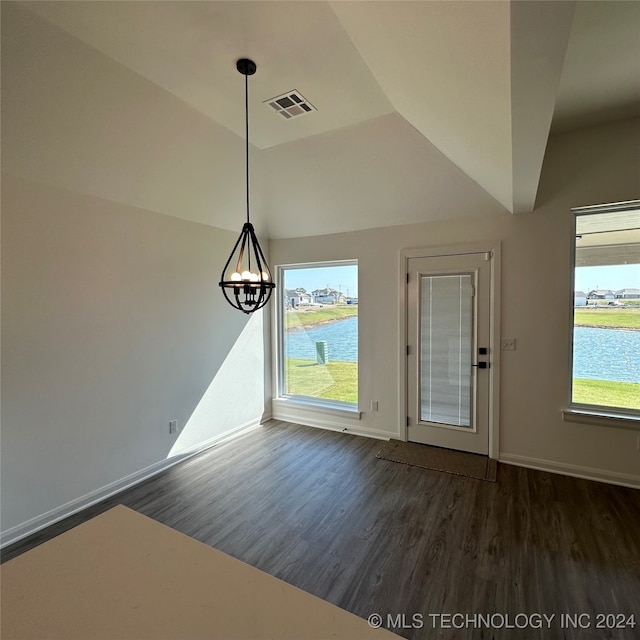 unfurnished dining area featuring dark wood-type flooring, vaulted ceiling, a water view, and an inviting chandelier