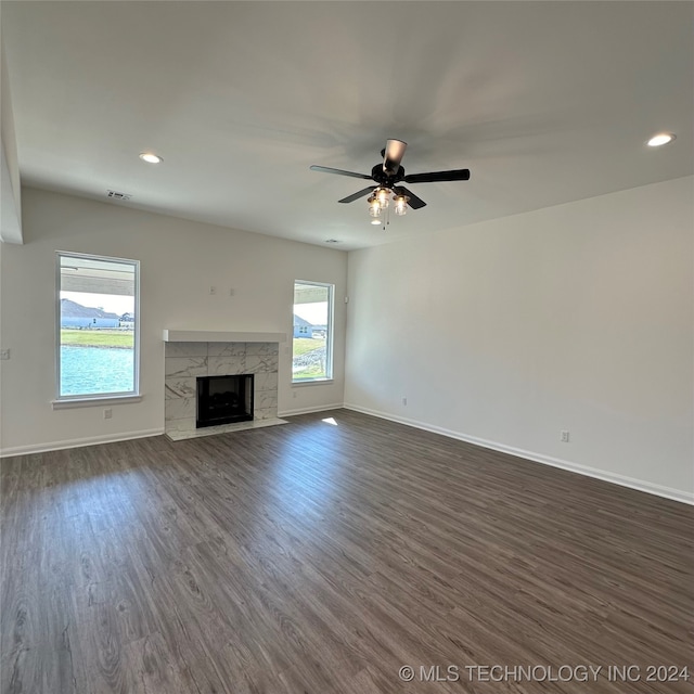 unfurnished living room featuring ceiling fan, a tile fireplace, and dark hardwood / wood-style flooring