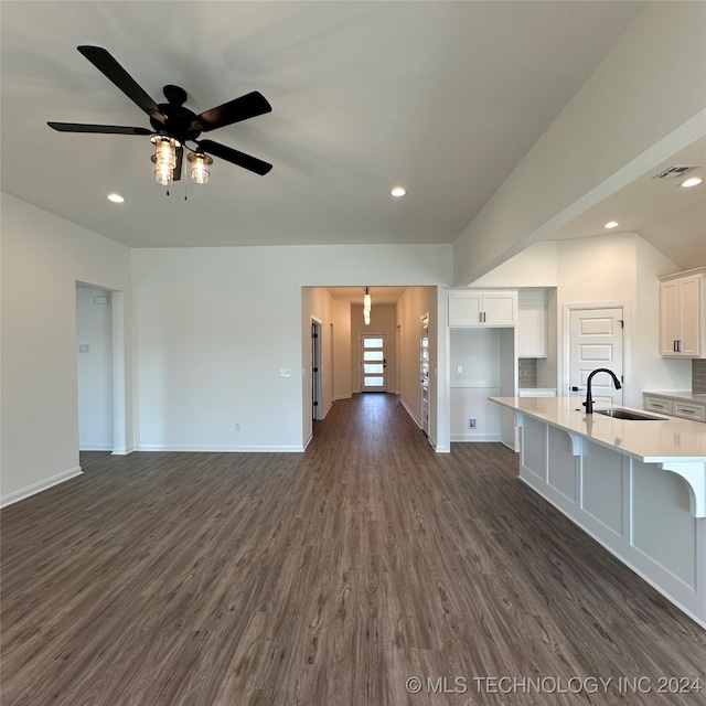 unfurnished living room featuring dark hardwood / wood-style floors, sink, and ceiling fan