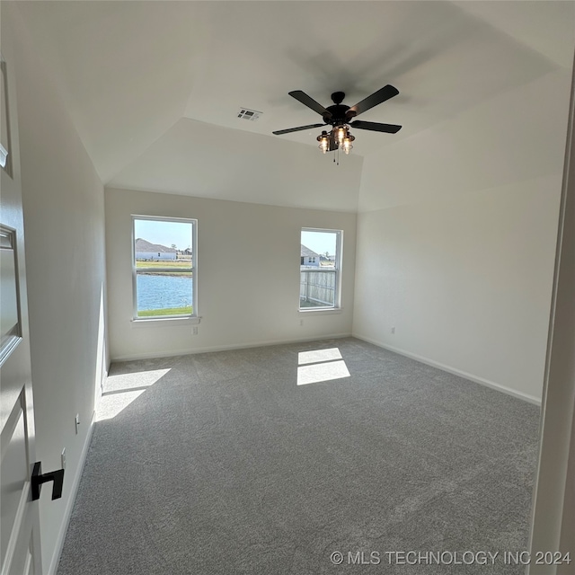 empty room with a water view, ceiling fan, carpet flooring, and vaulted ceiling