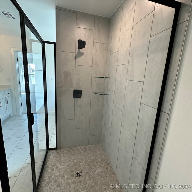 bathroom featuring vanity, a tile shower, and tile patterned floors