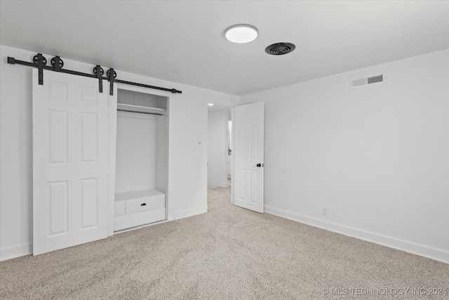 unfurnished bedroom featuring carpet flooring, a closet, and a barn door