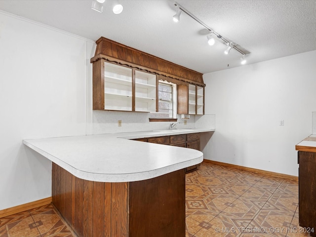 kitchen with backsplash, sink, light tile patterned floors, a textured ceiling, and kitchen peninsula