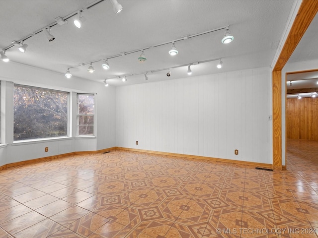 empty room featuring tile patterned flooring and wood walls