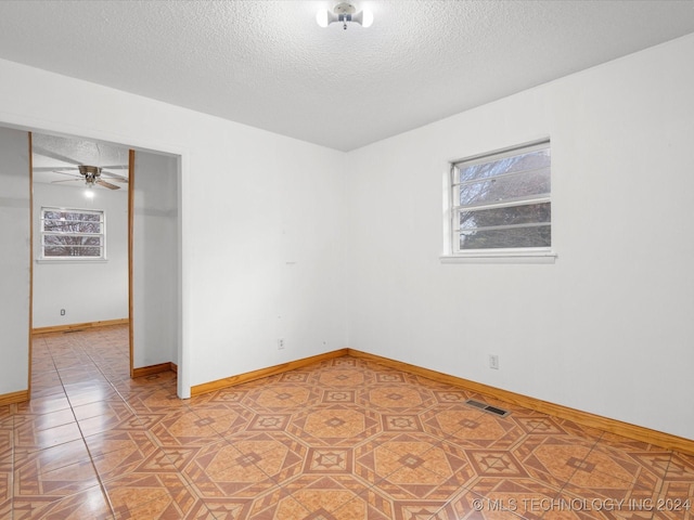 empty room with ceiling fan, tile patterned flooring, and a textured ceiling