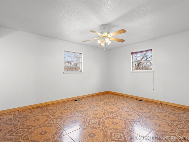 empty room with ceiling fan, plenty of natural light, and a textured ceiling