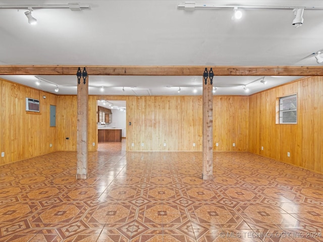 basement featuring electric panel, wooden walls, tile patterned flooring, and rail lighting