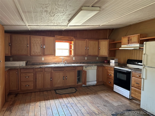 kitchen with wood walls, light wood-type flooring, sink, and white appliances