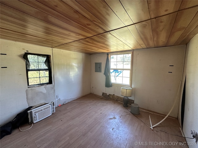 unfurnished room featuring light wood-type flooring, wood ceiling, electric panel, and a wall mounted air conditioner