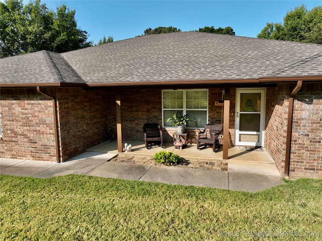 rear view of house with roof with shingles, brick siding, a patio, and a lawn