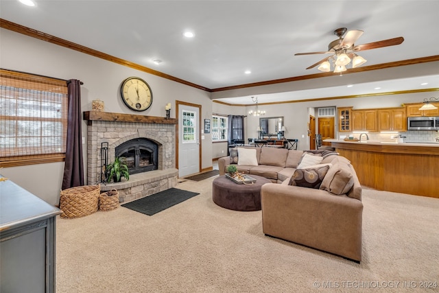 living room with a fireplace, crown molding, ceiling fan with notable chandelier, light colored carpet, and sink