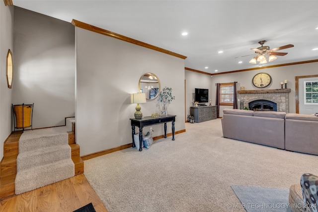 living room with ceiling fan, a fireplace, crown molding, and light hardwood / wood-style flooring