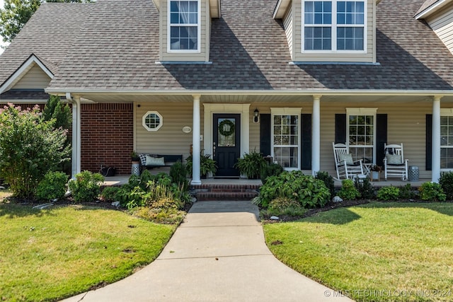 view of exterior entry featuring a lawn and covered porch