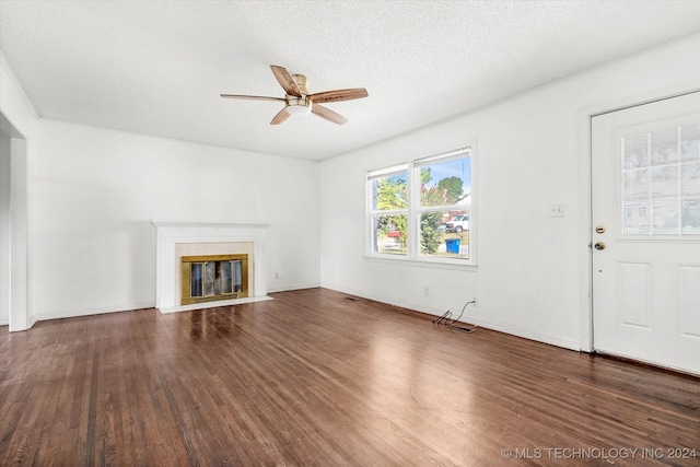 unfurnished living room featuring a textured ceiling, ceiling fan, a tiled fireplace, and dark hardwood / wood-style floors